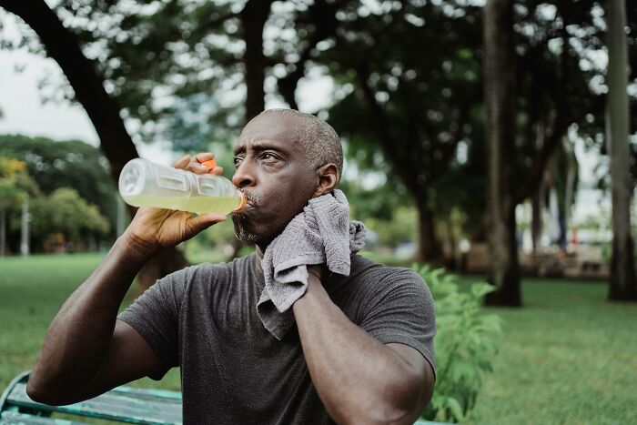 Man refreshing with a drink in a park, illustrating travel must-haves for a more convenient packing experience.