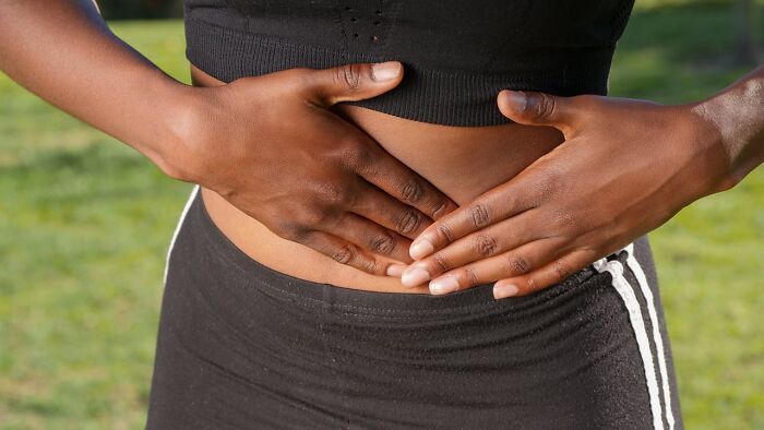 Person in activewear holding her abdomen, representing niche facts about the female body.