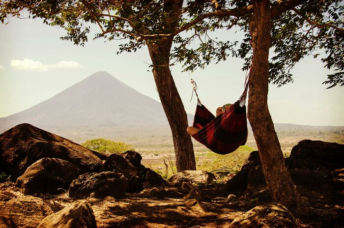 Person relaxing in a hammock between trees with a mountain view, highlighting the freedom and tranquility of being childfree.