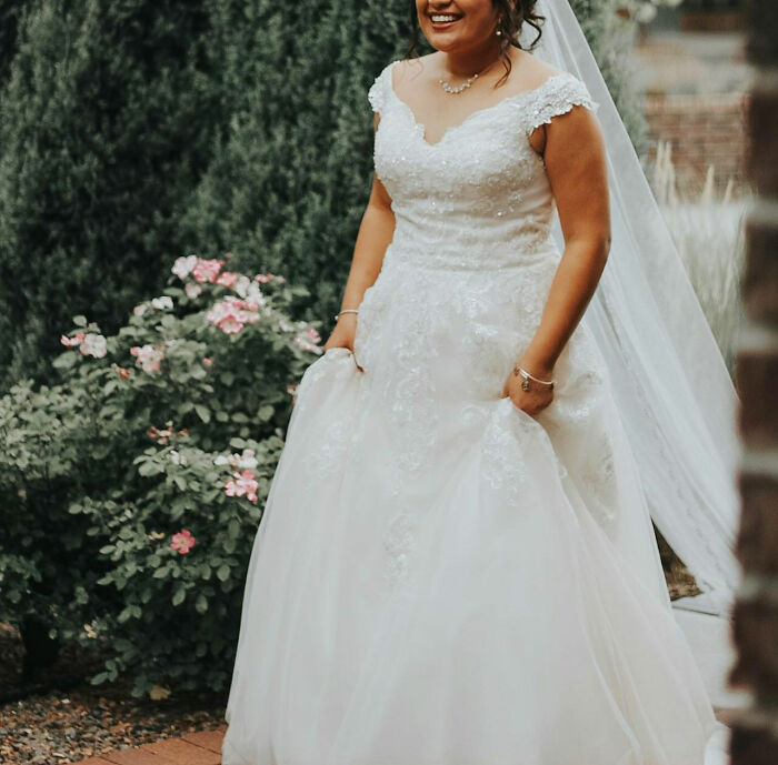 Bride in a beautiful white gown standing in a garden, offering a fresh perspective on wedding attire.