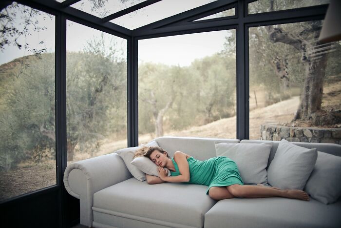 Person in a green dress relaxing on a sofa in a sunlit room, highlighting the childfree lifestyle benefits.