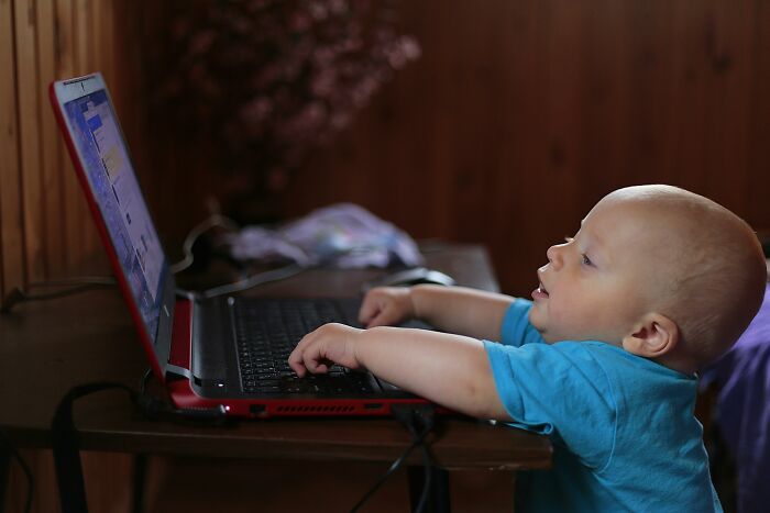 A baby in a blue shirt typing on a laptop, symbolizing humorous future predictions aged bad.