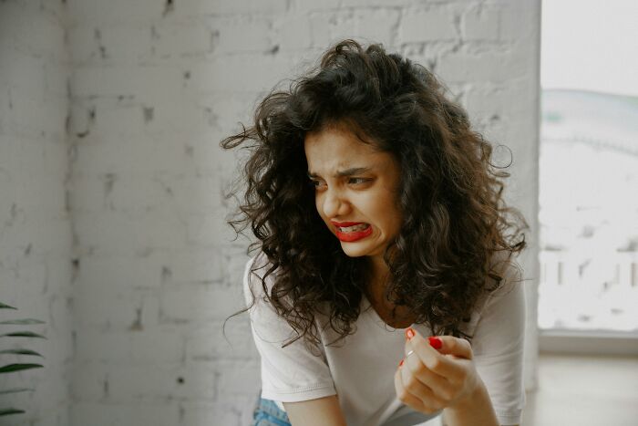 A woman with curly hair making a displeased expression, relating to childfree lifestyle discussions.