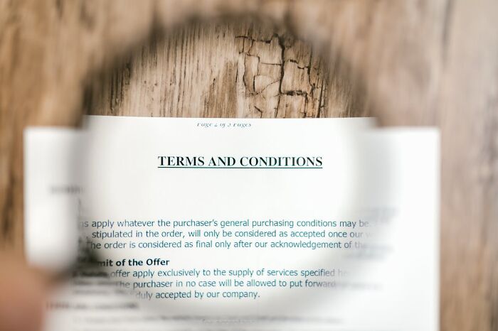 Magnifying glass over a &ldquo;Terms and Conditions&rdquo; document on a wooden table, symbolizing world facts and perspectives.