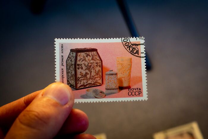 Person holding a vintage USSR postage stamp featuring ornate items, highlighting unique random world facts.