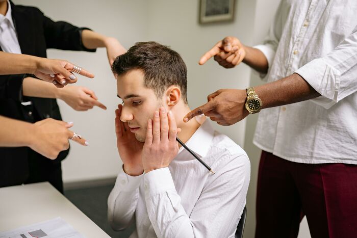 A man under stress surrounded by people pointing fingers, illustrating childfree lifestyle challenges.