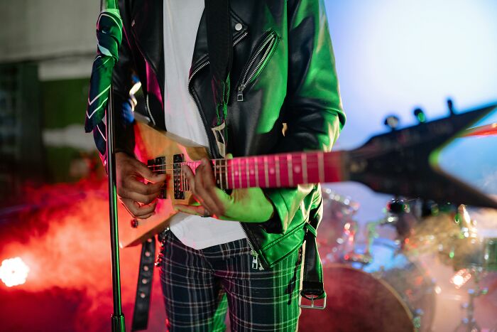 Guitarist in a leather jacket performing onstage, embodying a retro rock scene with lively stage lights.