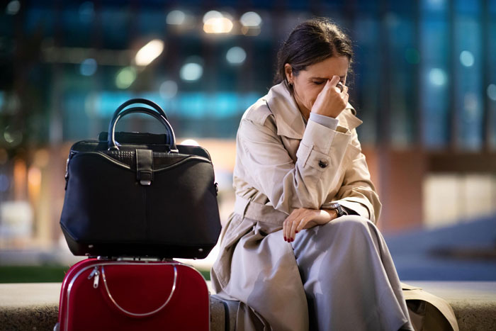 A woman sitting with luggage, looking distressed