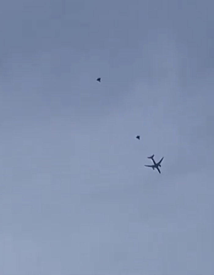 American Airlines plane escorted by fighter jets in the sky after bomb threat, viewed from below.