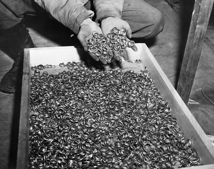 A person sorting through a large collection of metal rings in a box, representing rare historical artifacts.