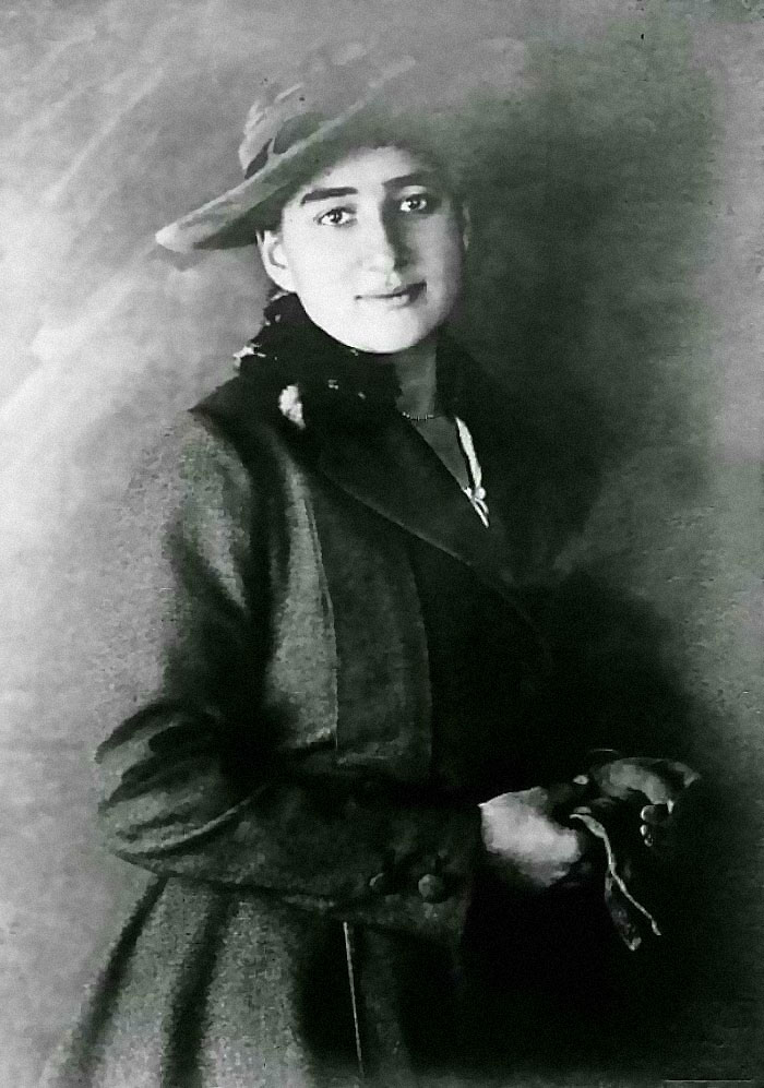 A woman in historical attire, wearing a hat and holding something, showcasing rare historical fashion.