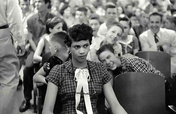 "Rare historical photo of a young woman in a crowded room, capturing a tense and solemn moment."