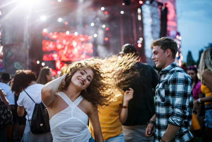 People enjoying a concert, with energetic dancing and vibrant stage lights in the background.