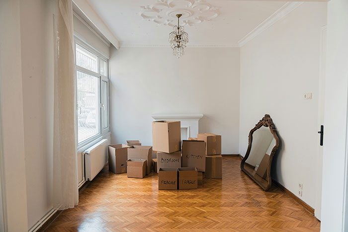 Empty room with moving boxes and mirror, symbolizing rent payment struggles involving dad’s ex-wife and son.