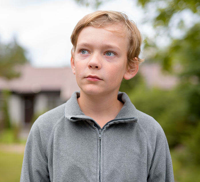 Young boy outdoors, wearing a gray jacket, related to dad's ex-wife needing rent help.