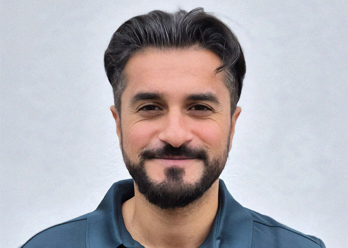 Man with a dark beard and a blue shirt, smiling, representing a scientist discussing restaurant spending strategies.