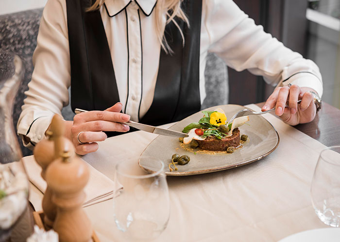 A person dining in a restaurant, illustrating ways restaurants manipulate spending with elegant meal presentation.