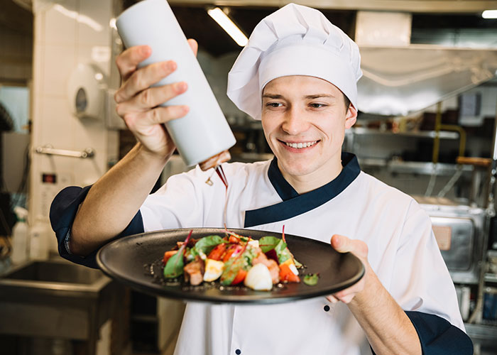 Chef garnishing dish, showcasing ways restaurants manipulate diners to spend more money.