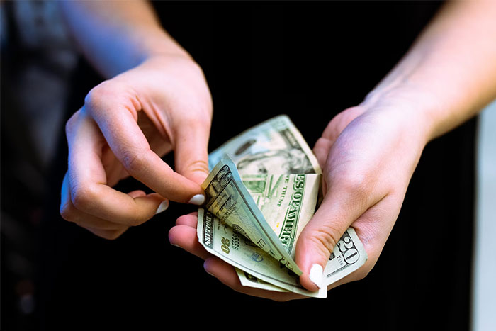 Hands holding a $100 bill and several $20 bills, related to a story of an elderly woman's insistent offer.