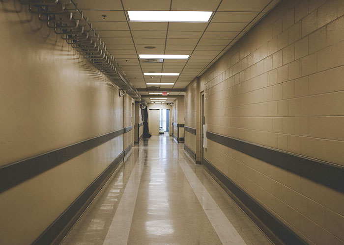 Empty office hallway with beige walls and fluorescent lighting, representing workplace tension.