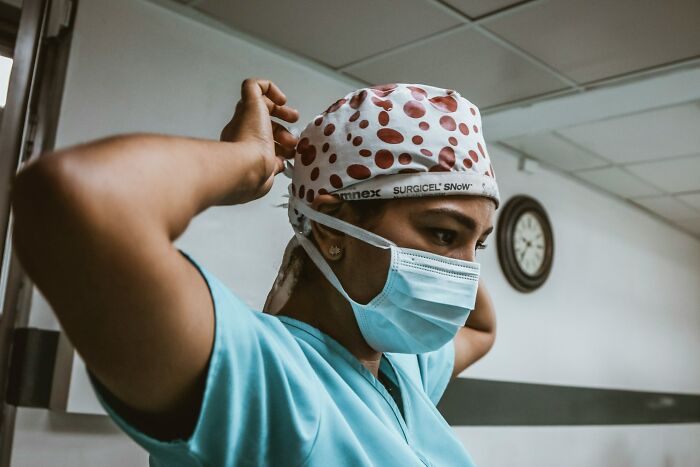 Medical professional adjusting a surgical cap, symbolizing female body healthcare.