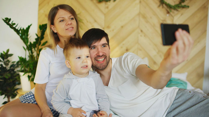 Family taking a selfie together, smiling and relaxed at home.