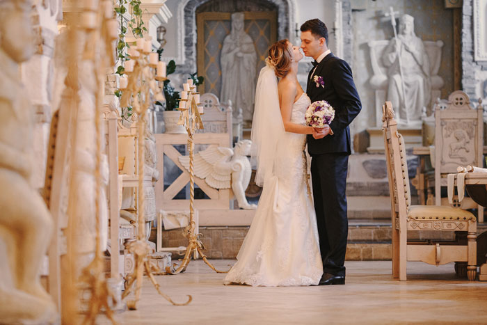 Bride and groom kissing in an ornate wedding venue, symbolizing family choices and wedding dynamics.