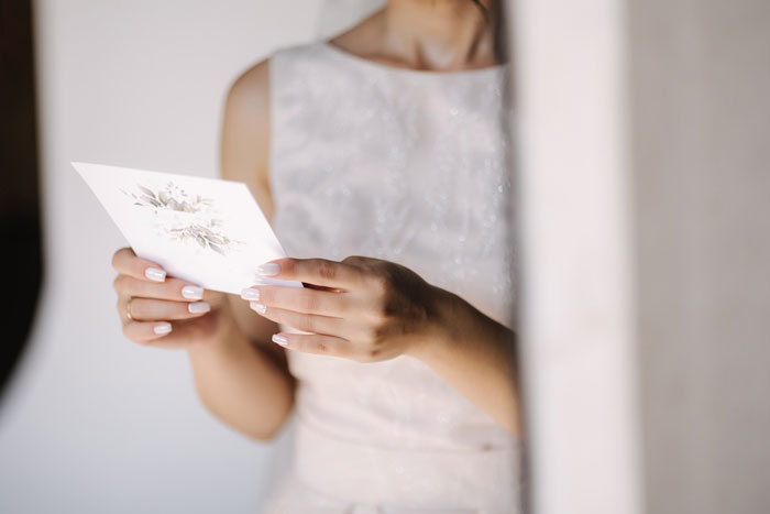 Bride holding a wedding invitation, reflecting on family dynamics surrounding her wedding day.