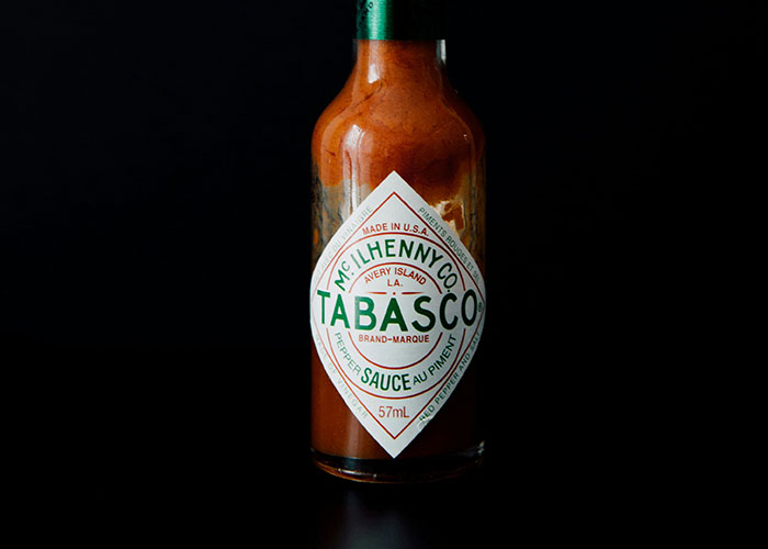 A bottle of Tabasco sauce against a black background, related to strange punishment stories.