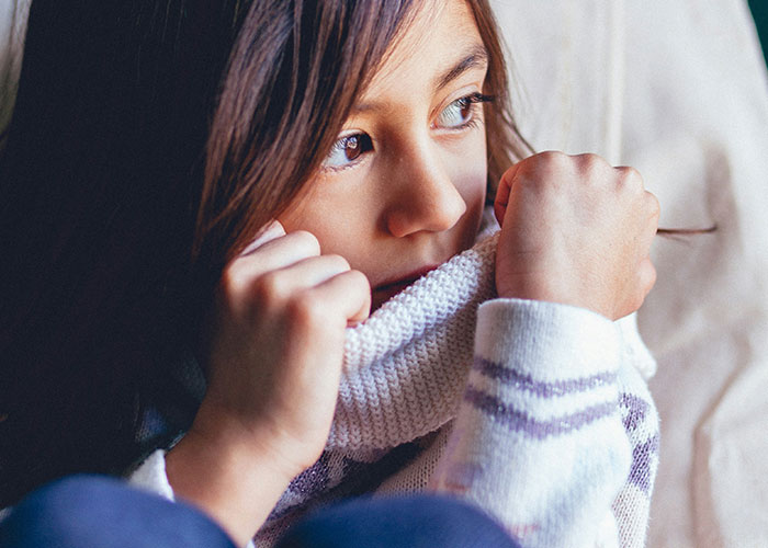 Child looking thoughtful, wearing a cozy sweater, contemplating a strange punishment received.