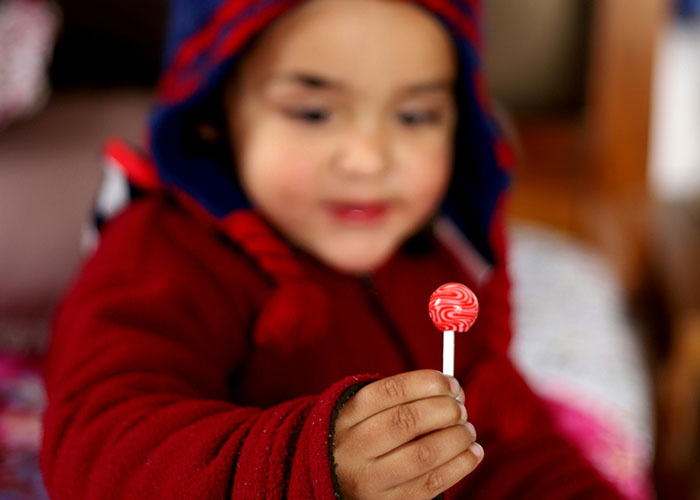 Child holding a lollipop, focusing on punishment and parenting themes.