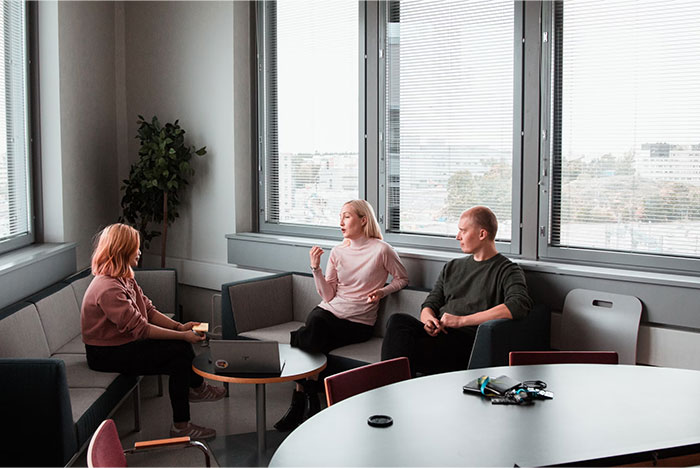 Three people in an office setting discussing topics related to corporate propaganda.