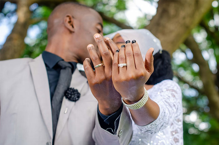 Couple showing wedding rings, highlighting corporate propaganda's impact on marriage norms.