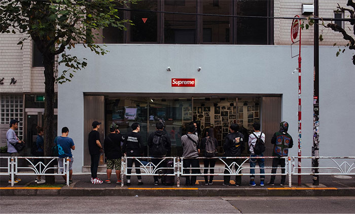 People queuing outside a Supreme store, illustrating corporate propaganda influence.