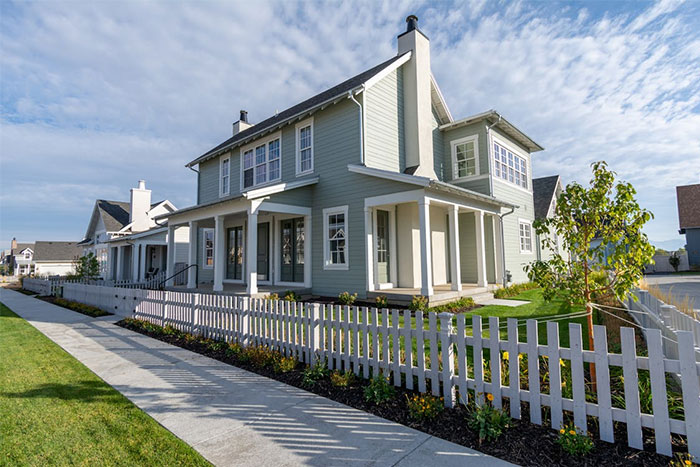 Modern suburban house with white picket fence, reflecting corporate propaganda influences in architecture.