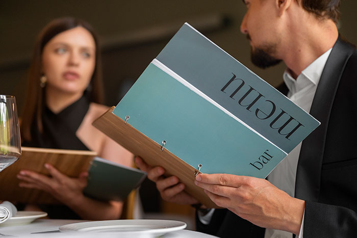 Man and woman in a restaurant examining menus, highlighting signs of a bad restaurant experience.