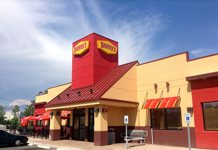 Exterior view of a Denny's restaurant under a clear sky.