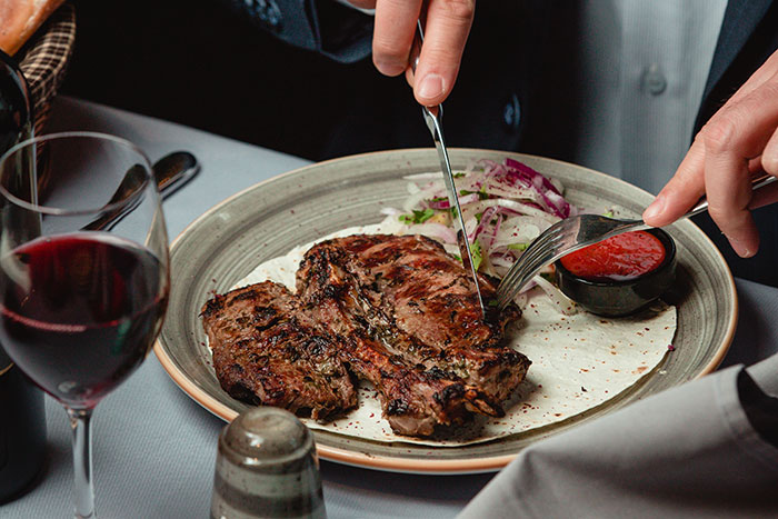 Person dining at a restaurant with a steak, indicating a potentially bad restaurant experience.