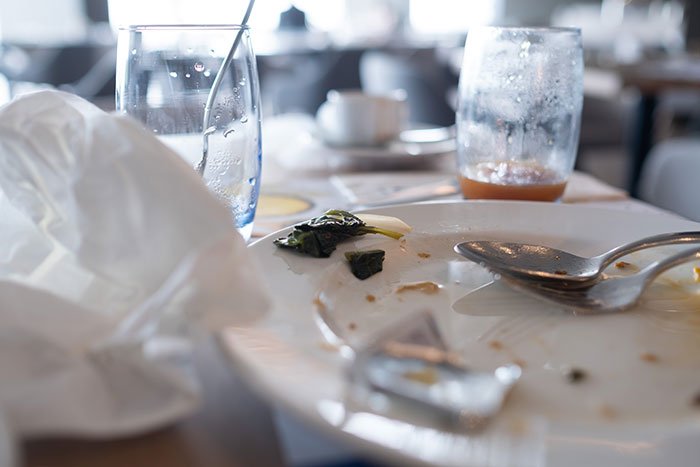 Messy table with dirty dishes and half-empty glasses, indicating a bad restaurant experience.