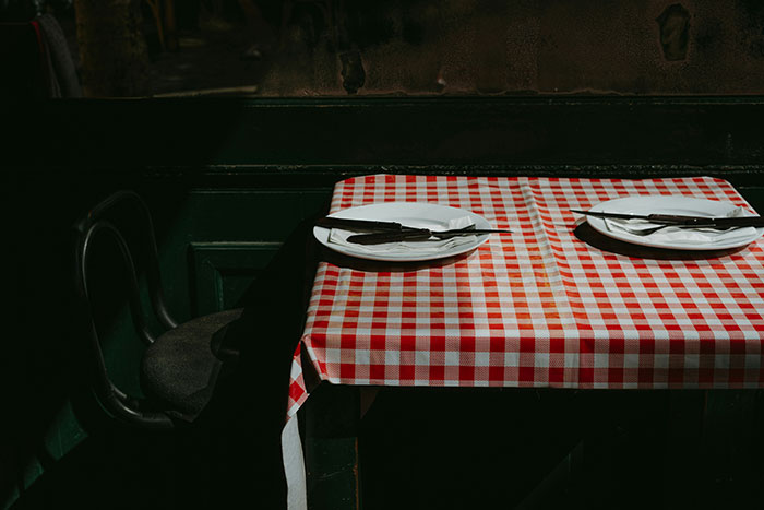 Empty table with a red checkered tablecloth in a dimly lit restaurant, a potential sign of a bad restaurant experience.