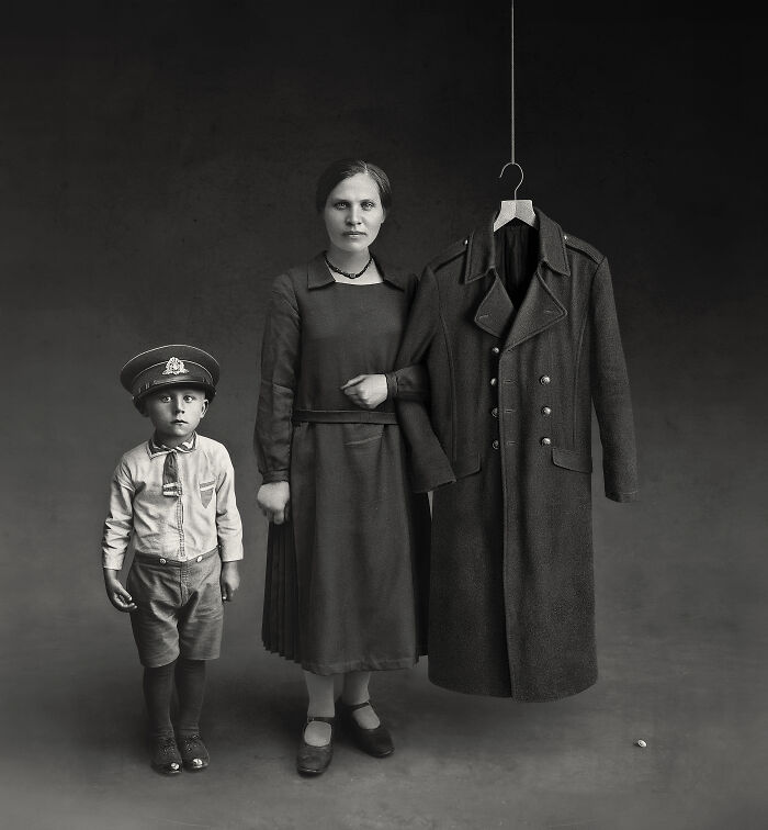 Woman with a child in vintage clothes, beside a hanging coat, from rare historical photos collection.