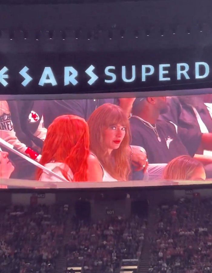 Taylor Swift on stadium screen during Super Bowl, crowd visible below.