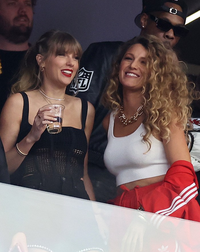 Two women smiling at an event, one holding a drink, with NFL logo in the background.