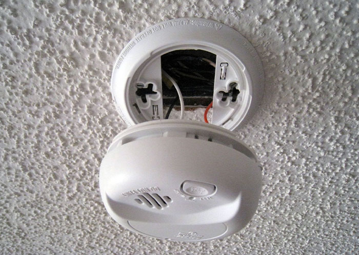 Smoke detector removed from ceiling, exposing wires; relates to paranoia theme.