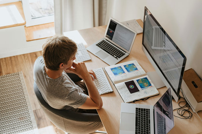 Person at a desk with multiple screens, attempting to optimize company structure and staff.