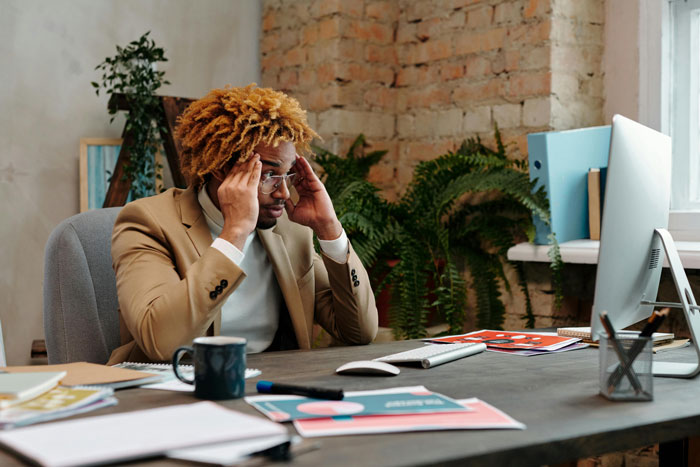 Businessperson at desk, stressed over company's structure and staff optimization efforts.