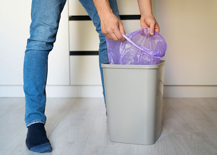 A man changing a trash bag in the kitchen, illustrating concepts about women learned after getting a girlfriend.