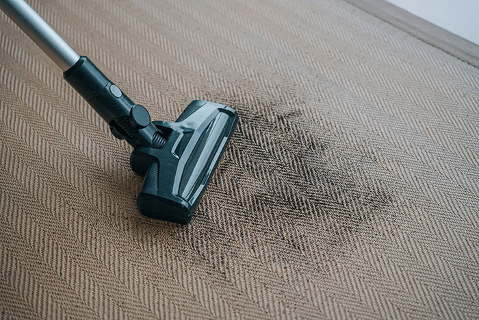 Vacuum cleaning dirty carpet, illustrating frugality in household chores.