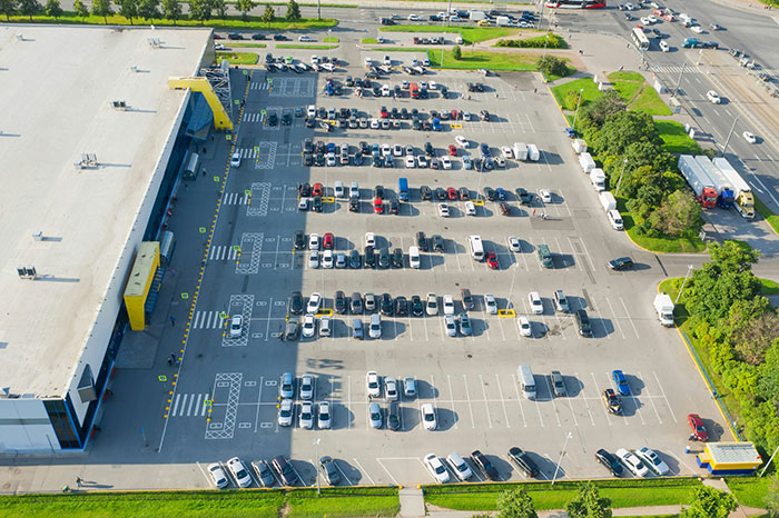 Aerial view of a large parking lot with many cars, illustrating frugality in urban planning efficiency.