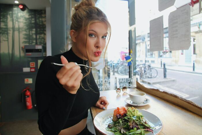 Woman in a cafe enjoying a salad, illustrating unique aspects of the female body.